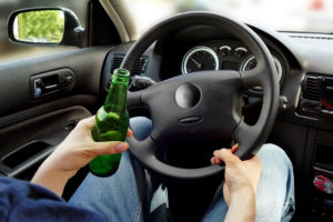 a person sitting in a car with a beer and steering wheel