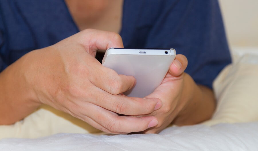a person laying in bed using a cell phone