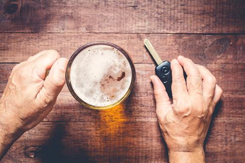 a man holding a beer and a car key