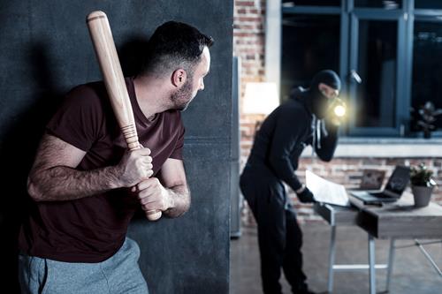 a man holding a baseball bat in front of a man in a dark room