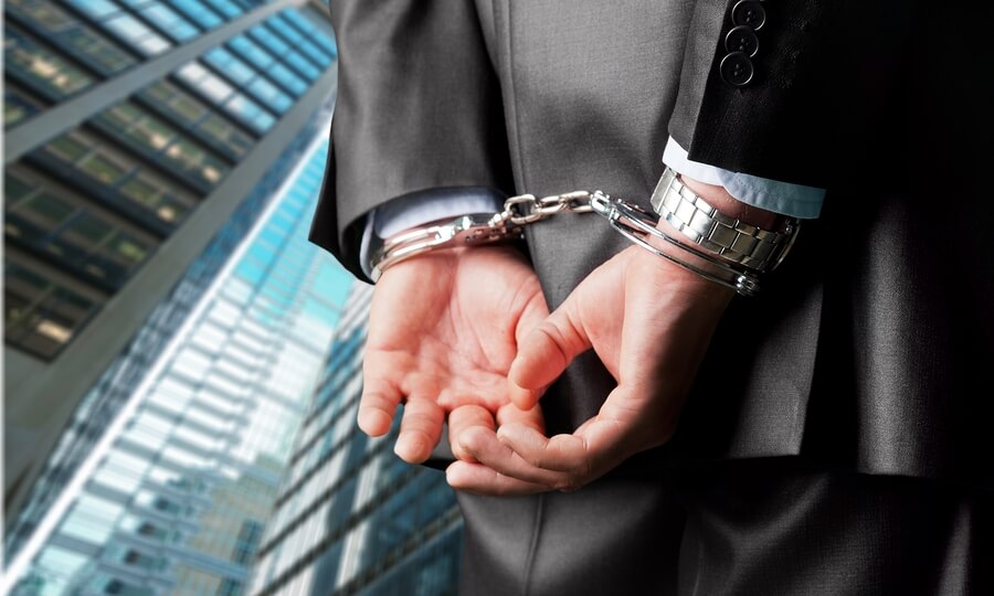a man in a suit and handcuffs is holding his hands