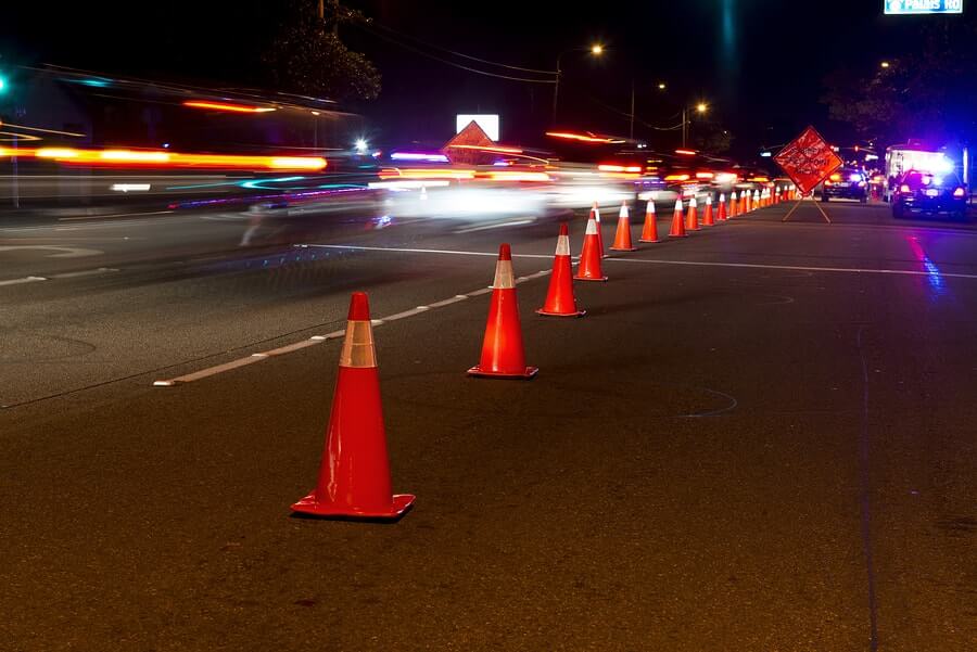 a long line of traffic cones on a city street at night
