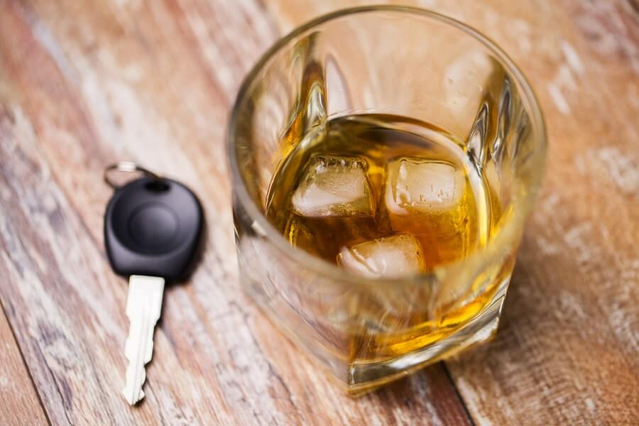 a glass of whiskey with ice cubes and a car key