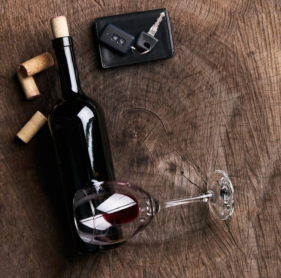 a bottle of wine, a glass and a key on a wooden table