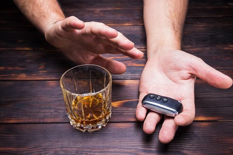 a man holding a remote control next to a glass of alcohol