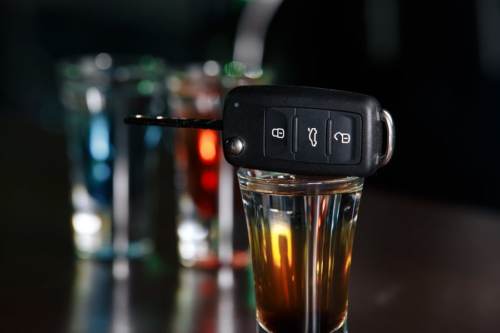 a car key is sitting on top of a glass of alcohol