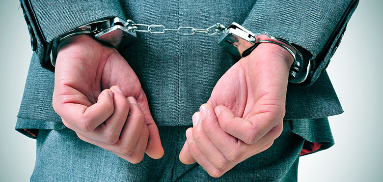 a man in a suit is holding handcuffs in his hands