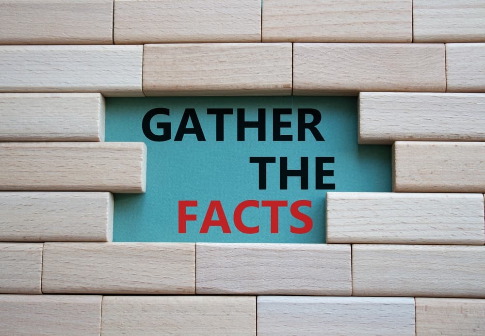 Wooden blocks with the phrase "Gather the facts" on a grey-green background, symbolizing the concept of business and gathering information.