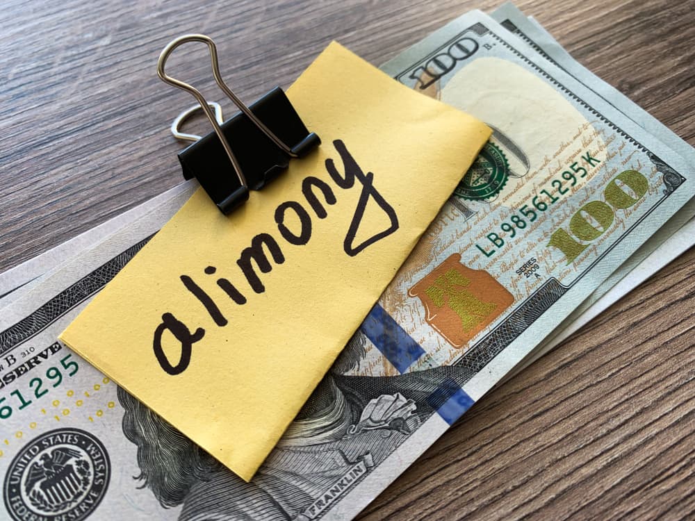 Stack of dollars with alimony sign - representing financial payments related to divorce and separation.