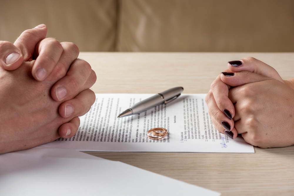 Hands of wife and husband signing divorce (dissolution, canceling marriage, legal separation) documents, filing divorce papers