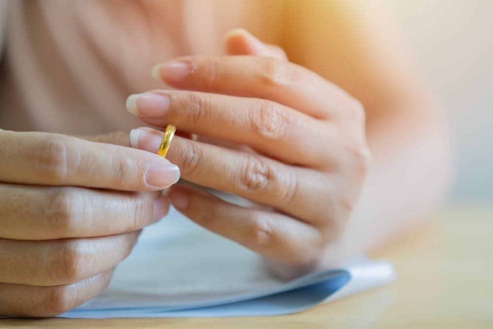 Woman taking off wedding ring and ready to sign divorce papers