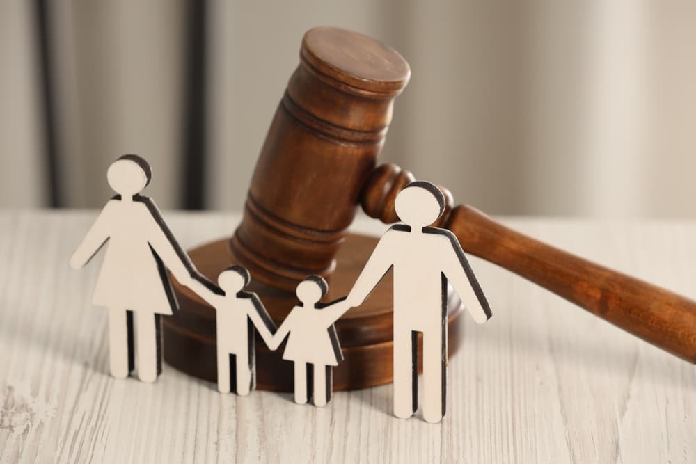 Gavel and figures of parents with children on white wooden table