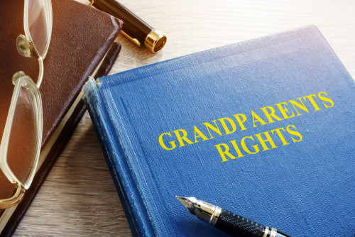 A legal book titled "Grandparents Rights" on a desk with a pen and glasses, signifying legal aspects of grandparent visitation and custody.