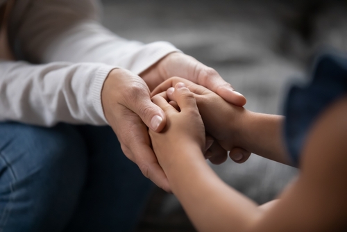 An adult holding a child's hands, representing love, support, and the importance of maintaining strong family relationships.