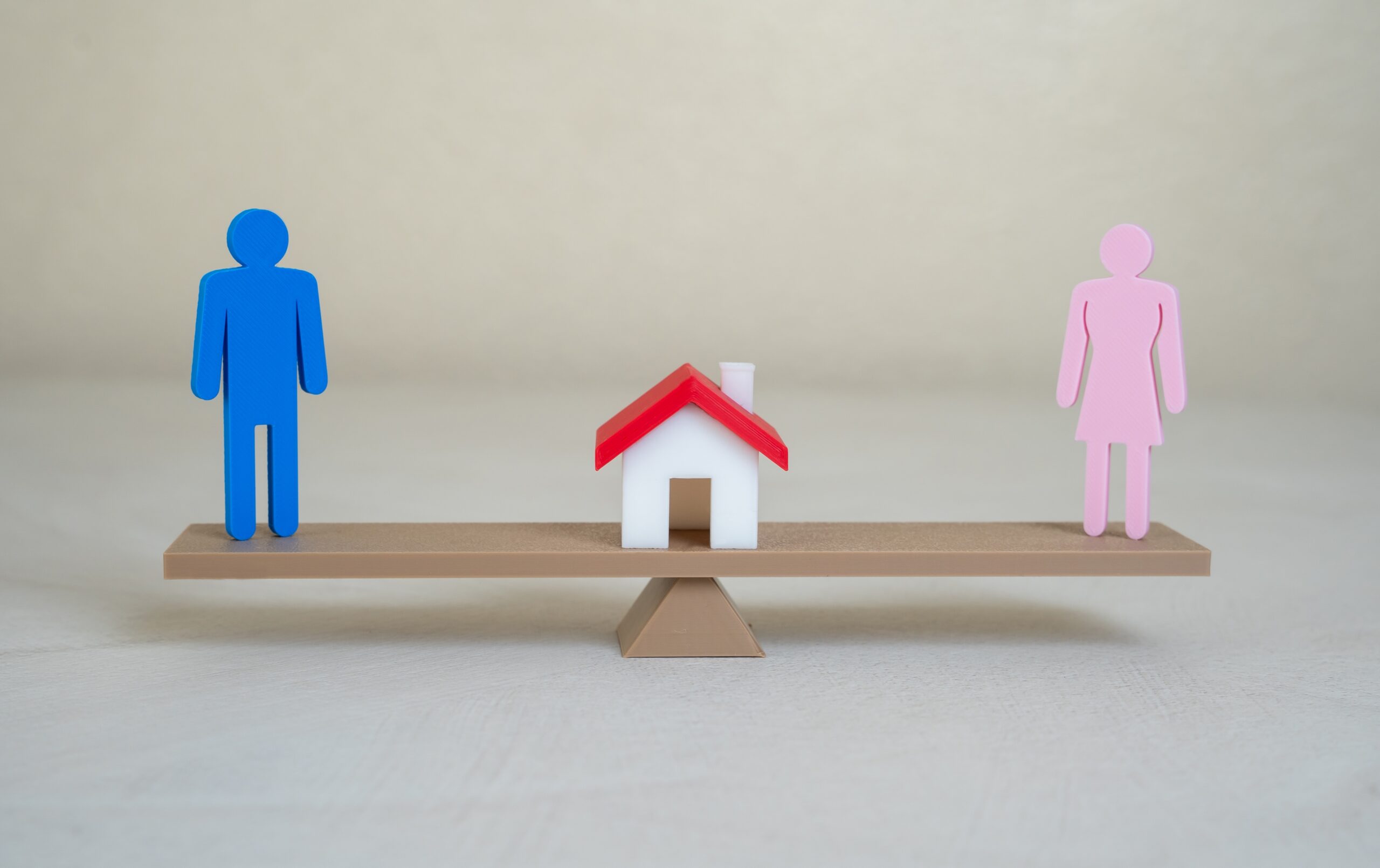 Balance scale with male and female figures and a house in the center, symbolizing division of the marital home in a Florida divorce